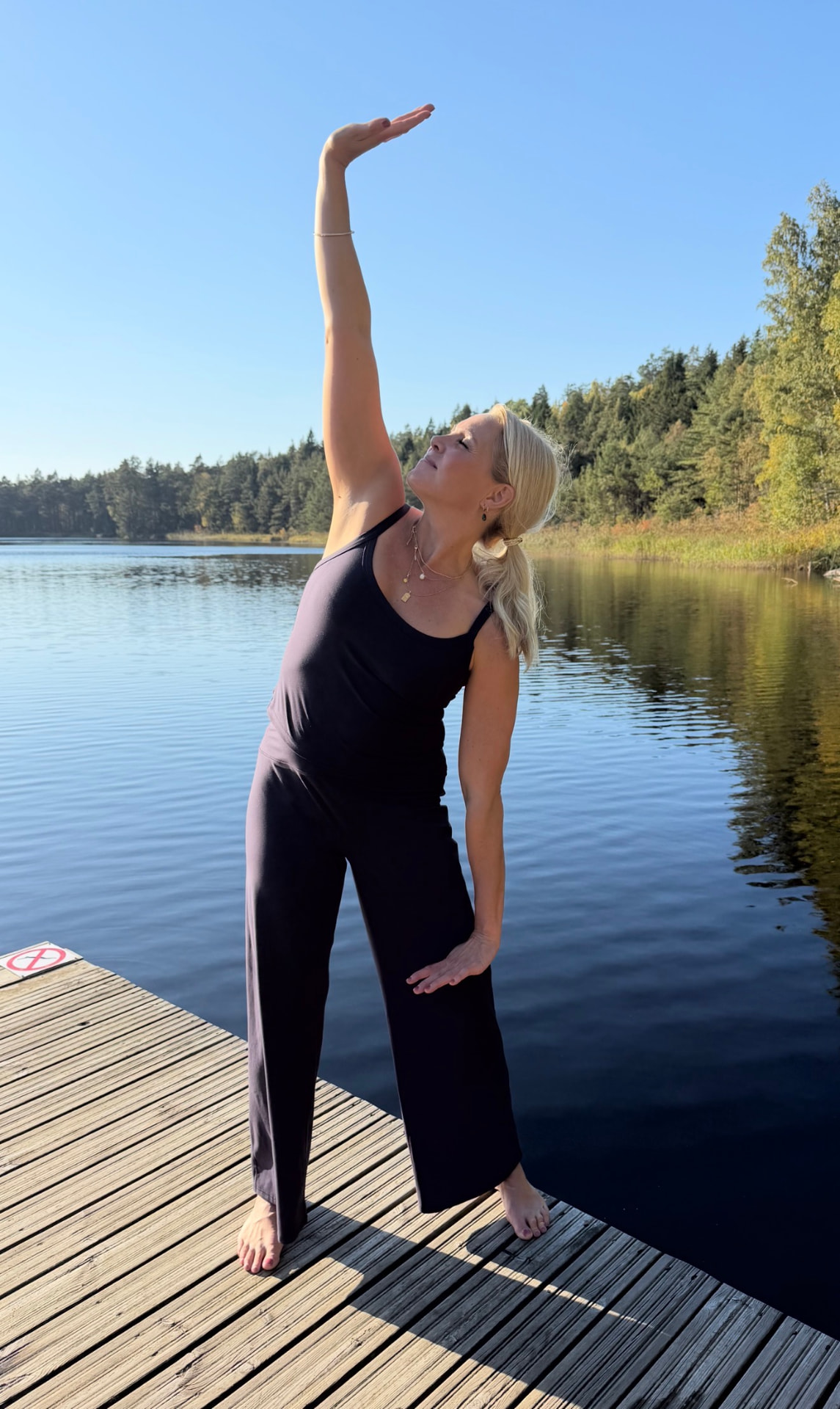 Johanna gör qigong på en brygga vid sjön